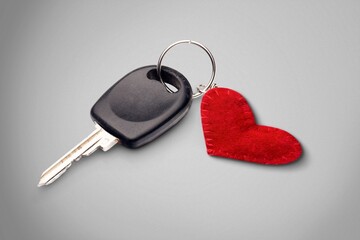 Car key with keychain and heart on gray background - obrazy, fototapety, plakaty