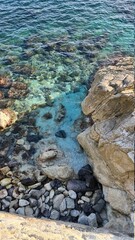 Savona, Italy - February 12, 2022: Panorama of the blue sea, light above the water, ocean sunrise. Some little waves in winter days. Long trees near the beach.
