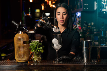 The young brunette Latina prepares a cocktail at the bar counter. job waitress profession