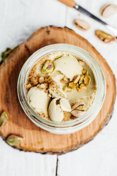 Homemade pistachio ice cream in a glass jar fresh pistachio over white background. vertical image. top view. place for text