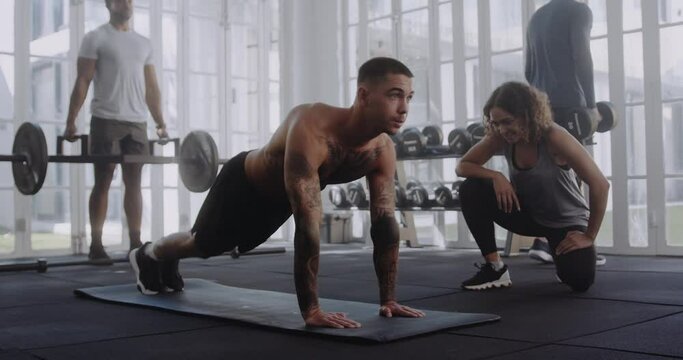 Young adult caucasian male doing exercise on mat with his trainer in modern style gym. Hi-5 celebration.