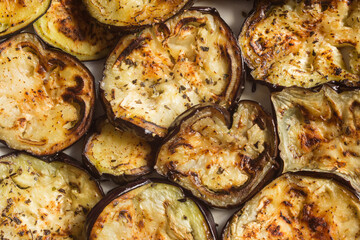 Overhead view of juicy oven-roasted eggplant slices topped with a mixture of minced garlic, basil, pepper parsley, and salt. Homemade and healthy recipes.