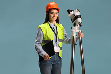 Female geodetic surveyor posing with a measuring instrument on a tripod