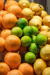 close-up of a pallet of fresh citrus fruits for sale at the local market. You can see yellow lemons, green limes and oranges