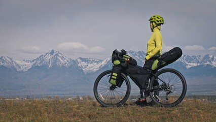 The woman travel on mixed terrain cycle touring with bikepacking. The traveler journey with bicycle...
