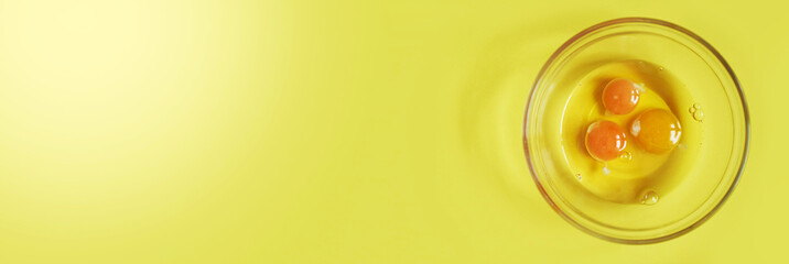 Banner.Three raw eggs on a yellow background with a space to copy. Breakfast preparation concept. High quality photo