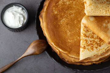 A stack of thin pancakes with fresh sour cream