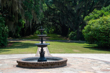 A black fountain with oak trees in the background 
