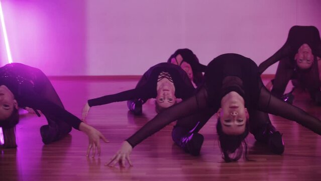 Group of sexy women in black clothes sitting on their knees and bending their back backwards