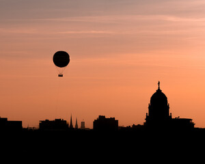 Fototapeta na wymiar Berlin, Germany: Berlin's skyline silhouette from above. Hot air balloon in the sky at sunset. View from the roof of the Humboldt Forum.