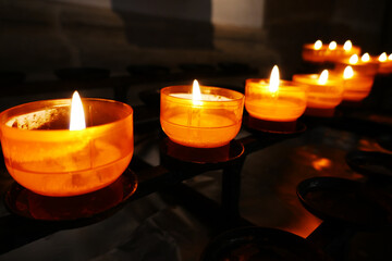 Row with yellow prayer tea lights in a roman catholic church