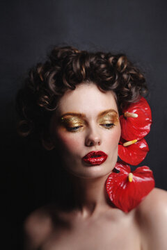 Beautiful woman with golden makeup and red flowers