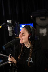 Young female singer recording a song in studio