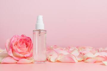 Obraz na płótnie Canvas Serum bottle or facial and body gel with rose on pink background, copy space, natural skin care cosmetics