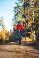 Obraz premium Young likeable lady with a lovely realistic smile while recreationally sporting. Cyclist riding fat bike in Finnish wild nature. Vuokatti area. Cycling clothing and helmet. Cycling