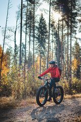 Fototapeta na wymiar Young likeable lady with a lovely realistic smile while recreationally sporting. Cyclist riding fat bike in Finnish wild nature. Vuokatti area. Cycling clothing and helmet. Cycling