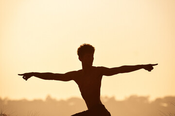 Fototapeta na wymiar Young man doing yoga at the red orange sunset in the hills landscape