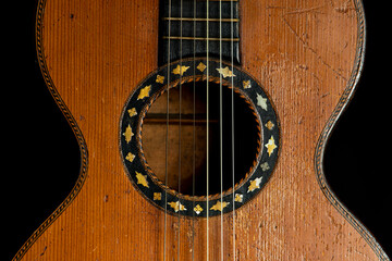 Detail of ancient classical guitar on black background