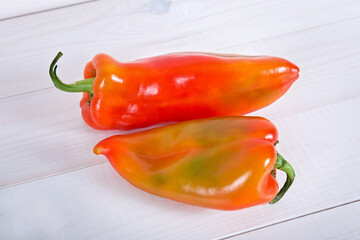 Two bulgarian sweet bell peppers on white wooden background.