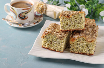 Homemade sweet cake with poppy seeds, cut into slices on a plate on a blue background, horizontal format