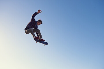 Fototapeta na wymiar A rad day at the skate park. A young man doing tricks on his skateboard at the skate park.