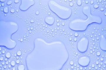 Cosmetic moisturizing liquid drops on purple blue pastel background. Toner or lotion. Hyaluronic serum