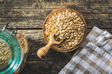 Fototapeta na wymiar Uncooked brown lentils. Raw legume in bowl on wooden table.