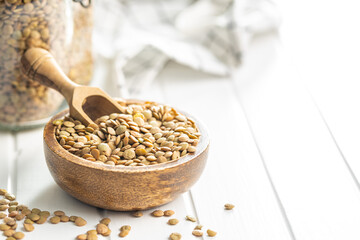 Uncooked brown lentils. Raw legume in bowl on white table.