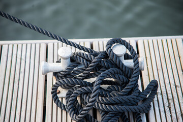 Obraz premium Double cross bollard or bitteng with a tied rope on the dock. towing mooring gear