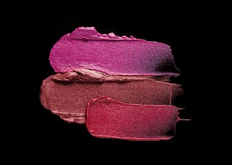 Fototapeta premium Lipstick abstract strokes smudges background texture multi colored red pink fuchsia chocolat glitter shimmer isolated on black background