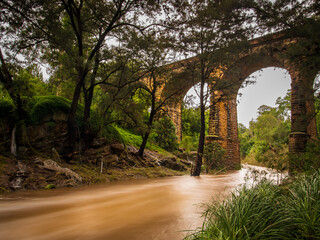 Fototapeta na wymiar Historic railway viaduct with flooded creek below