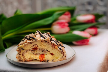 an appetizing piece of birthday cake on a silver platter and fresh terry tulips blurred in the background