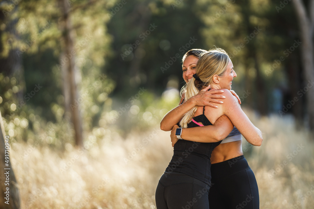 Poster Two Female Friends Meet Outdoors To Do Some Exercise Together