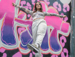 a modern young dancer poses in front of a street graffiti backdrop
