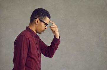 Young african american man thinking put finger to forehead studio portrait headshot. Black businessman freelancer brainstorming searching problem solution and inspiration. Side view