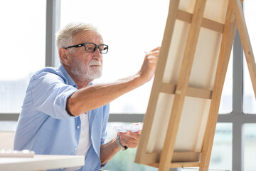 senior man painting a picture from paintbrush in free time
