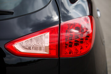 Back view of new black car. Closeup headlights of car. Black premium city crossover, luxury SUV...