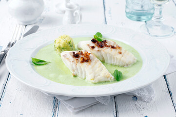 Traditional skrei cod fish filet mashed potatoes in basil champagne foam served as close-up on a...