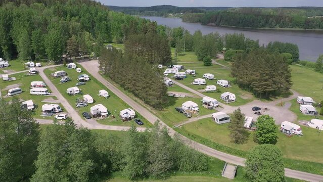 Awesome aerial shot of a caravan park next to a lake. Awesome trailer lifestyle and a perfect vacation opportunity. Aerial geology shot with the drone slowly moving backwards.