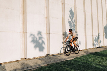 Fototapeta premium Muscular man riding black bike on city street