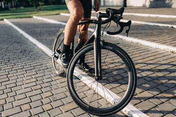 Cyclist in sport shoes sitting on black bike on fresh air