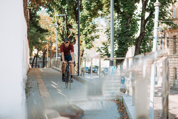 Active man in helmet riding black bike on city streets