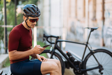 Man in sport clothes using smartphone after cycling