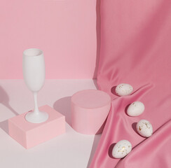 Pastel pink Easter composition with wine glass, satin curtain and white eggs. Suitable for Product Display and Business Concept. Modern aesthetic. Happy Easter.