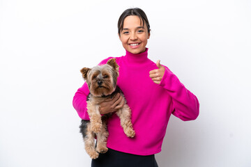 Young hispanic woman holding a dog isolated on white background with thumbs up because something good has happened