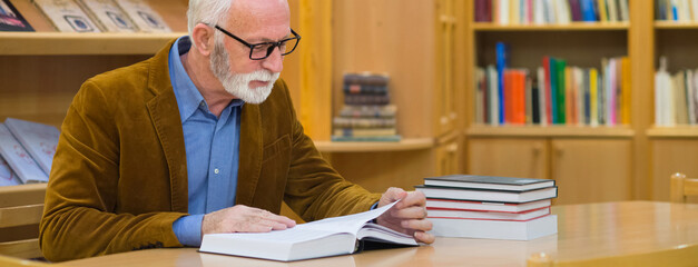 Senior man reading book in the library