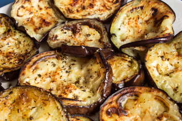 Detail of a slice of oven-roasted aubergine with the rest of the vegetables cut surrounded as a background. Easy and vegetarian recipes.