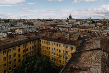 Photo of yellow old residential building and rusty rooftops in center of Saint Petersburg. Saint Isaacs Cathedral on background. Informal Petersburg. Travel destination. Vacation concept.