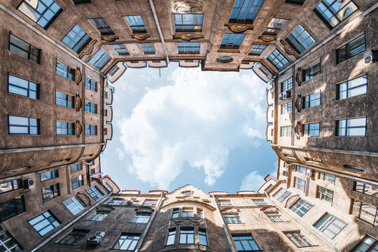 Enclosed courtyard of old residential house in Saint Petersburg, Russia. Blue cloudy sky. Copy space.