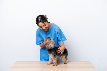 Young veterinarian woman with dog on a table isolated on white background with happy expression